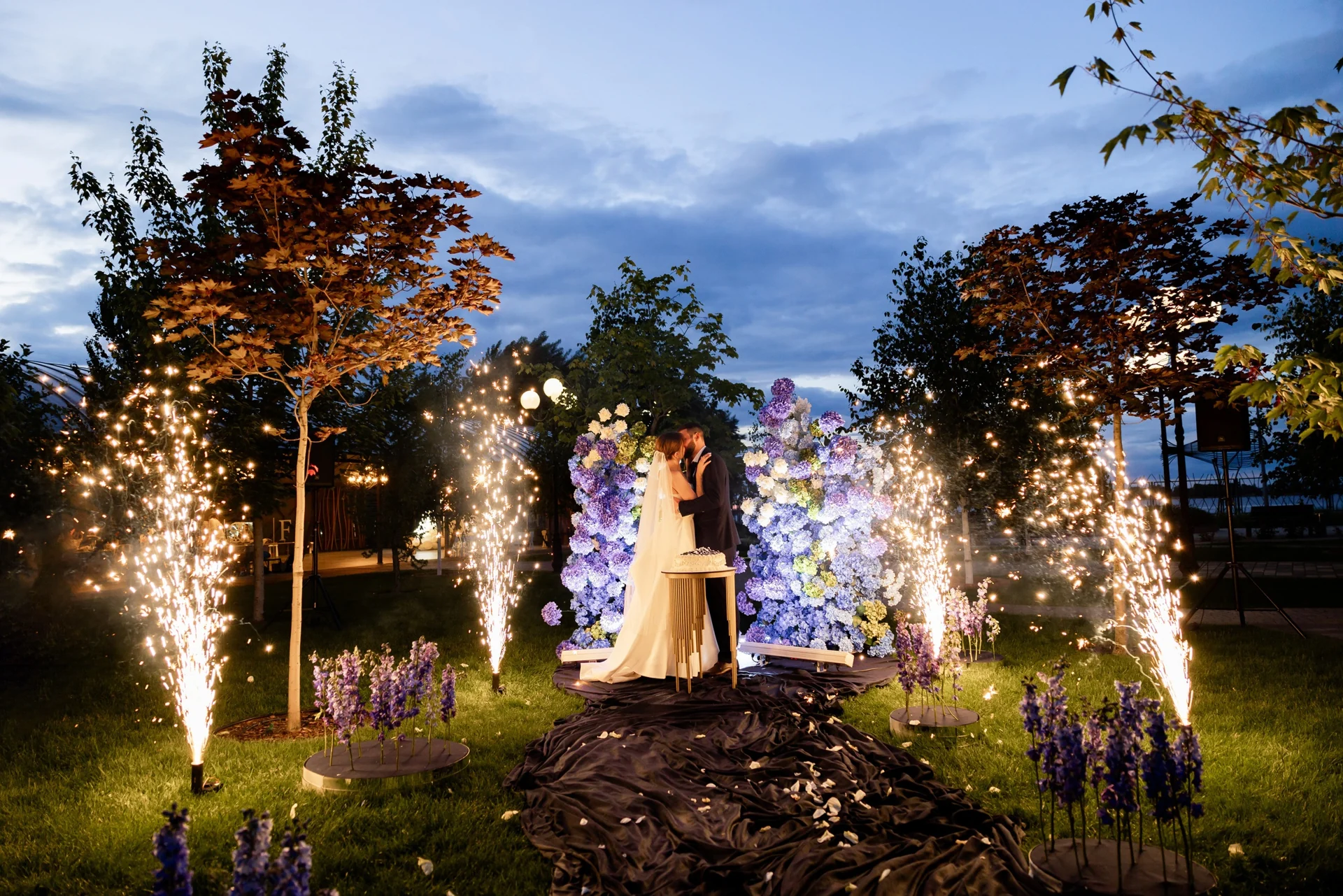 An outdoor cake reveal framed by spark fountains, a SHOW PLUS project